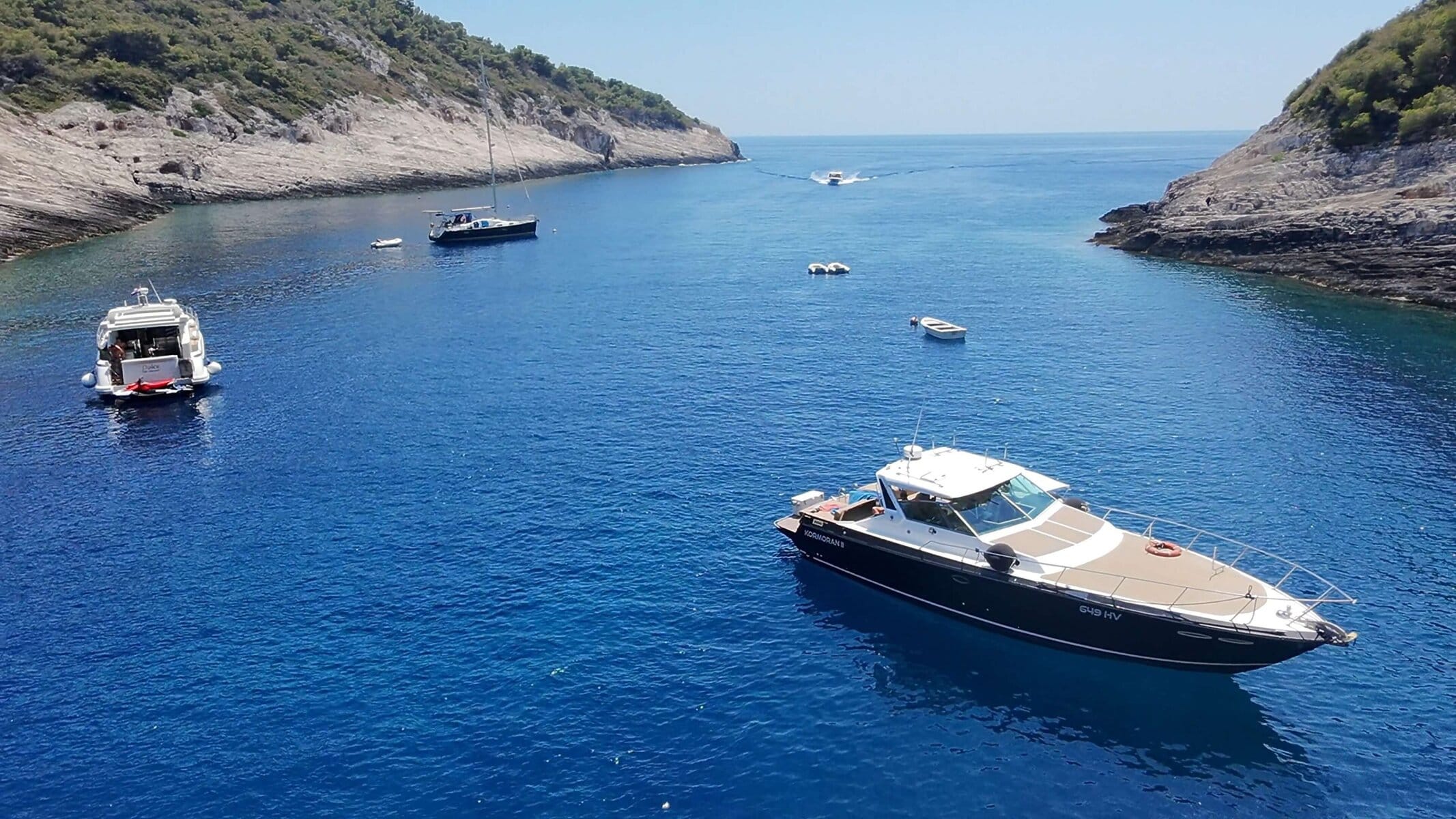 Blog what to bring on a boat tour in Hvar - view of a boat anchored in the famous Stiniva Cove on Vis Island, surrounded by high cliffs and turquoise sea.